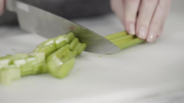 Curring vegetables on a white cutting board to cook vegetarian white bean soup. alt