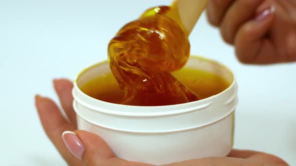Sugar paste or honey wax for epilation, dripping from wooden wax sticks - depilation and beauty.