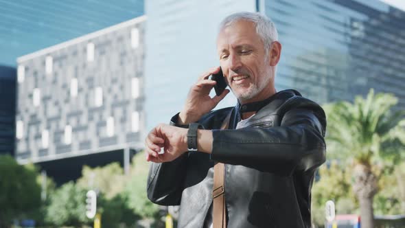 Caucasian man out and about in the city street talking on his smartphone alt