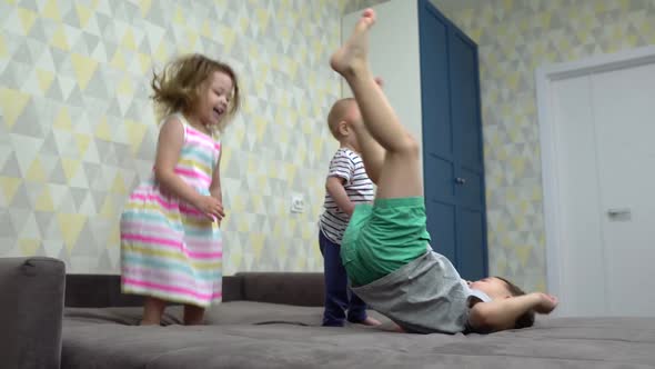 Three Small Children Jumping on Bed Indoors at Home, Having Fun.