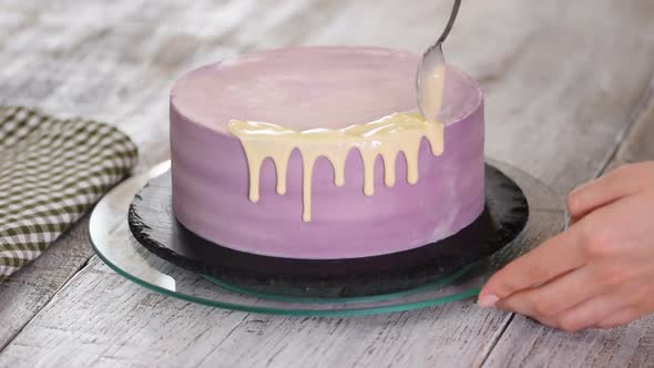 Preparation of a holiday cake. The girl pours liquid white chocolate on the cake.	 alt