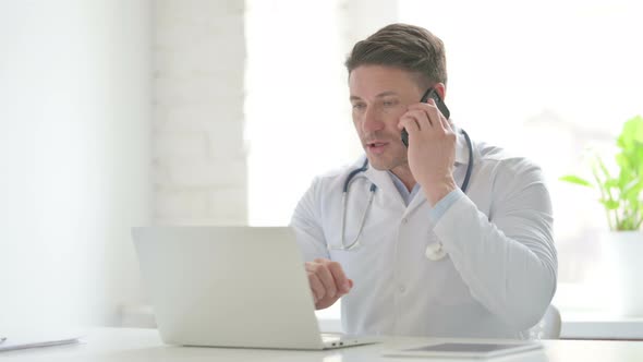 Male Doctor with Laptop Talking on Phone alt