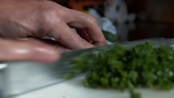 Close Up View of Knife Cutting Multiple Chives Into Pile of Small Vegetable Pieces alt