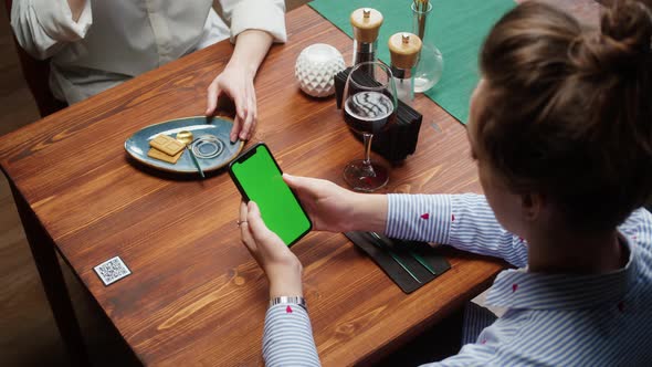 Woman Using Smartphone with Chroma Green Screen Online Menu in Cafe alt