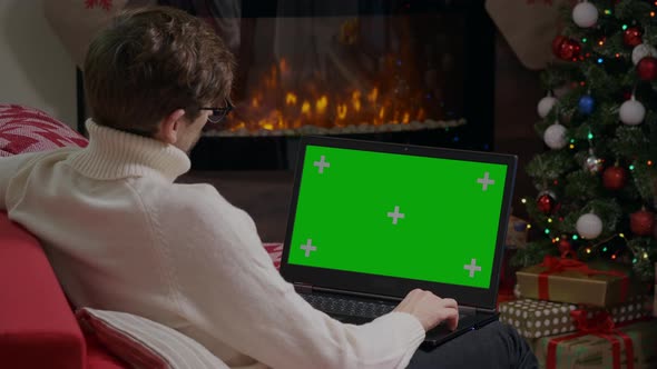 Male watching video content on Green Screen Chroma key laptop. alt