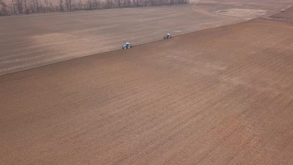 Agricultural Work in the Field, Two Blue Tractors Plow the Land