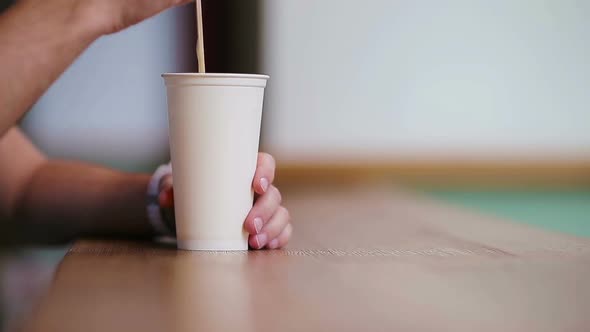 Closeup of Male Hands Stir the Sugar in a Glass with Coffeee in Cafe. alt