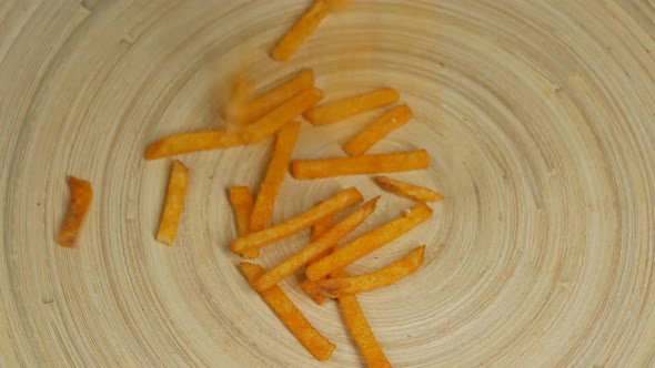 Orange Potato Spicy Long Chips Fall From Above Into a Wooden Cork Bowl