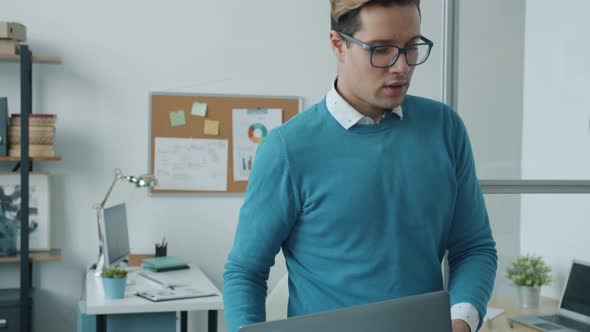Slow Motion of Businessman Walking in Office Carrying Laptop Then Talking to Female Colleague alt