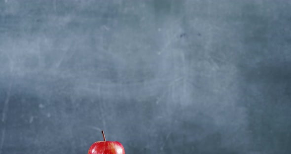 Apple on book stack with color pencil on table alt