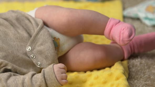 Tiny Adorable Baby Girl Lying on Draw-Sheet While Mother Is Busy, Lack of Time alt