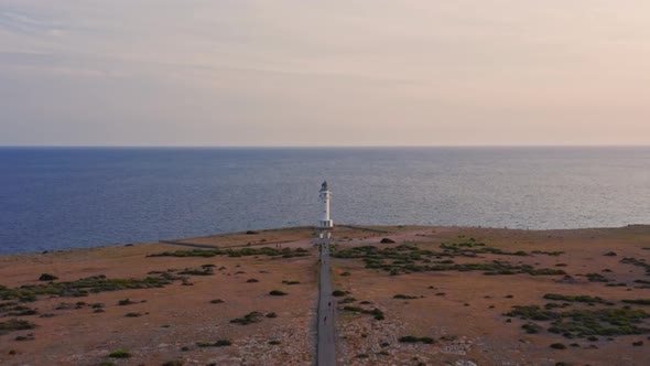 Lighthouse cupola dolly in, empty road in dry plain and calm blue sea alt