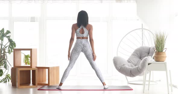 Athletic fit girl doing fitness aerobic exercises for booty in living room. alt