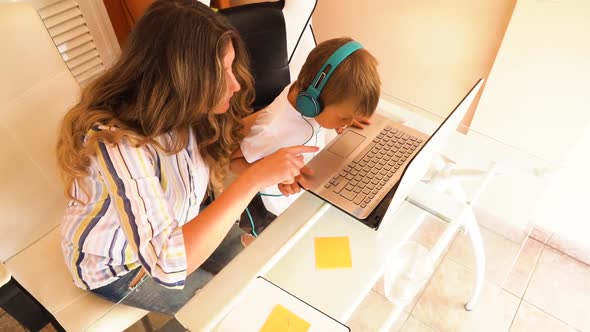 Mother helping her son with online lesson alt