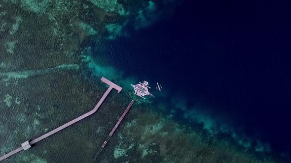 Jukung boat seen from above in Raja Ampat islands Indonesia on a coral reef pier diving spot, Aerial alt