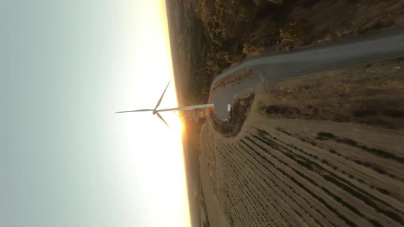 Vertical Dynamic Fpv Shot of White Operative Wind Turbine While Beautiful Sunset