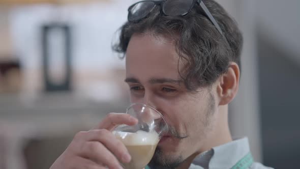 Headshot Portrait of Young Handsome Brunette Caucasian Man with Brown Eyes and Mustache Drinking alt