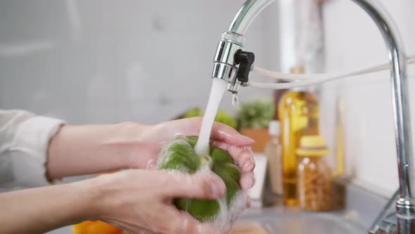 Close up of Woman Hand Tap water Washing a Fresh Organic Bell Pepper