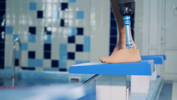 Man with Prosthetic Leg Stands Near a Pool While Training alt