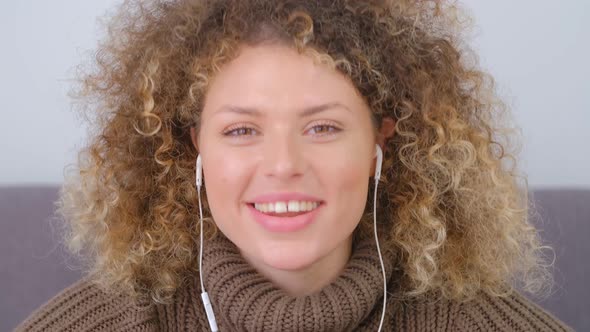 Video portrait of cheerful curly female in headset talking on camera with toothy smile in 4k video alt