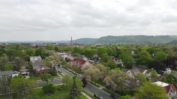 View of older historic neighborhood in valley with mountains in background and lots of clouds.