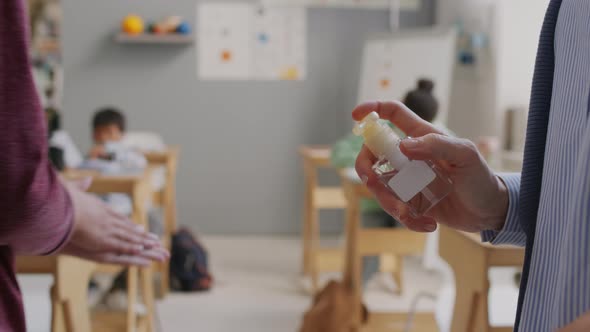 Teacher Putting Sanitizing Hands of Kids in Class alt