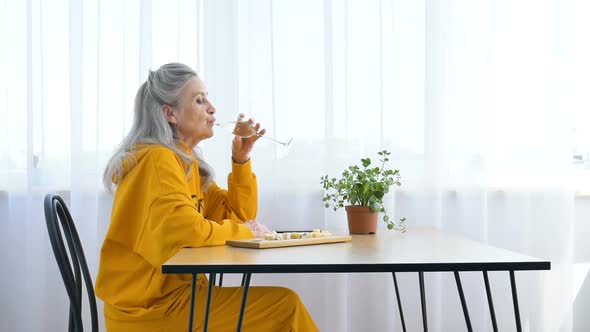 Beautiful Old Grandmother with Grey Hair and Face with Wrinkles Sitting at the Table at Home on alt