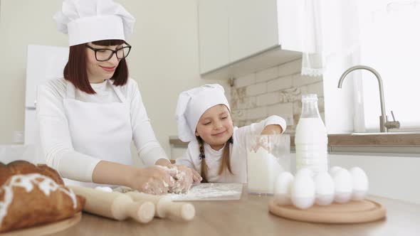 Charming Adorable Attractive Beautiful Caucasian Sprinkle Flour on the Dough While Smiling to Young alt