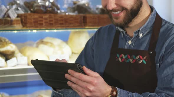 Cropped Close Up of a Male Baker Using Digital Tablet Working at the Bakery alt