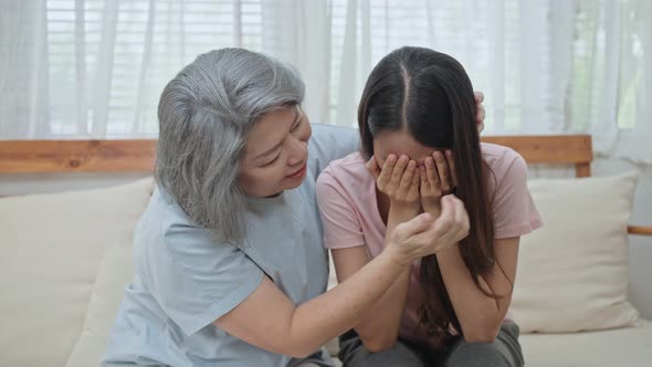 Asian senior mother consoling and comforting upset depressed young girl daughter crying for problem. alt