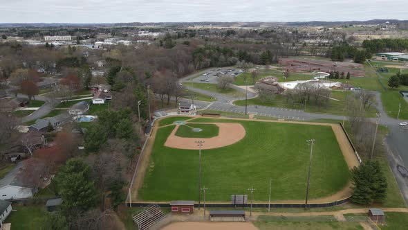 Overhead view of sports complex and school building with ball field and swimming pool.