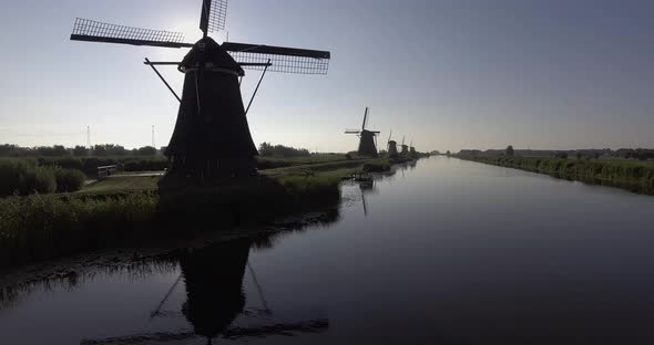 A drone shot panning forward, around Dutch Windmills during sunrise alt