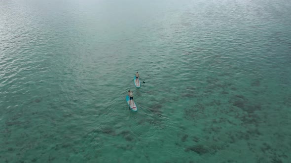 Surfers Couple on Surfing Board Man and Woman Swimmers Relaxing on Blue Surfboards Top View alt