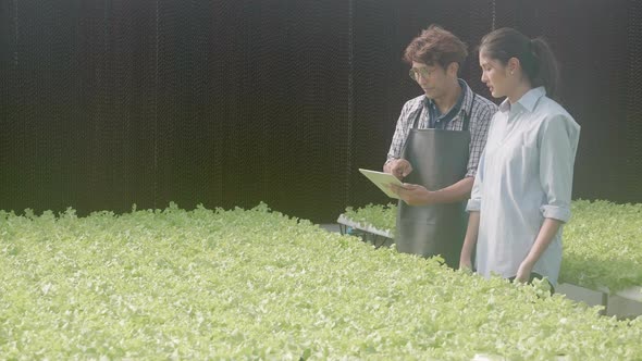 Young asian man walking and holding tablet computer talking for recommend vegetables with customer. alt