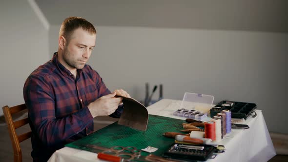 A Craftsman Sanding a Piece of Leather for a Travel Case. The Full Cycle of Production Traveled a