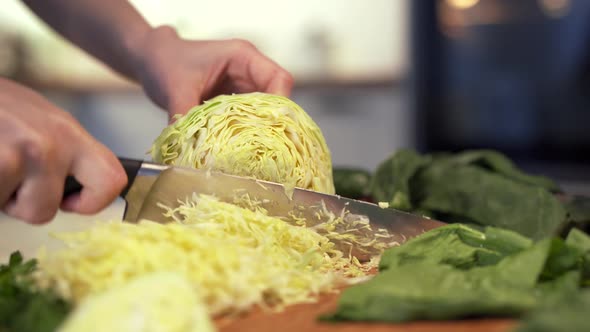 Woman's Hands Cutting a Fresh White Cabbage on Wooden Cutting Board Using Kitchen Knife