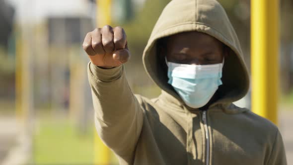 hooded black man raises his fist in protest against the racial discrimination alt