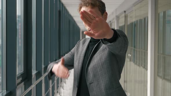 Young stylish man busissman looks at camera, holds out his hand in front of him. Stop action. Stand alt