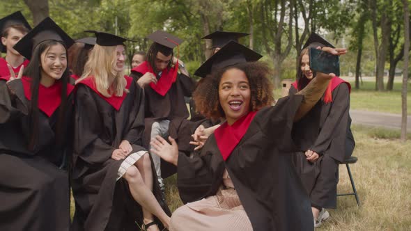 Portrait of Carefree Students in Graduation Gowns Making Selfie at Graduation Day alt