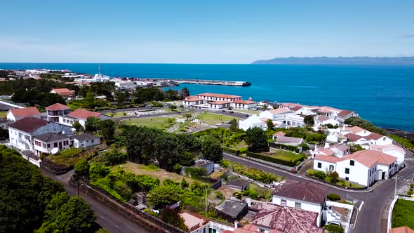 Aerial view over São Roque do Pico town flying towards the bluish Atlantic Ocean in Pico Island, Azo alt