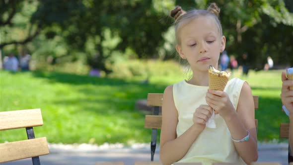 Little Girl Eating Ice-cream Outdoors at Summer in Outdoor Cafe