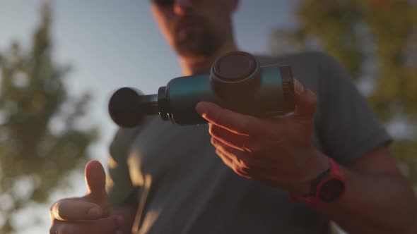 An Athlete Massages with a Percussion Therapy Gun to Relieve the Pain of Muscle Aches After a alt