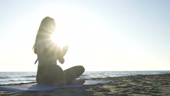 Young Caucasian Woman Practicing Yoga on the Beach Near Calm Sea