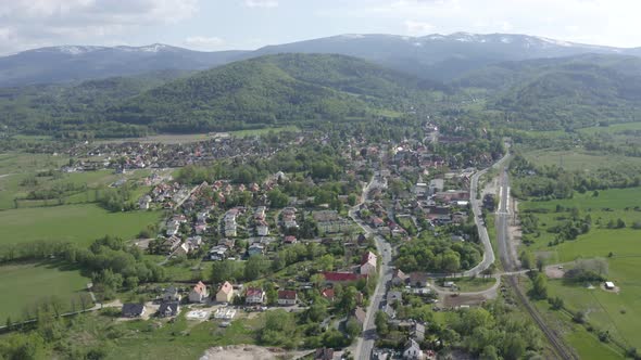 Flying above small city under Mountains 