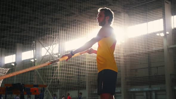Pole Vaulting Indoors - a Man in Yellow Shirt Standing on the Track with a Pole and Preparing for alt