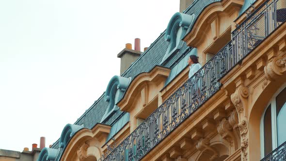Young girl in a white shirt on a balcony in Paris alt