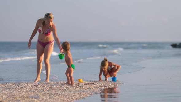 Mom Plays with Her Children Daughter and Baby Building Beads and Castles Decorating Them with Shells alt