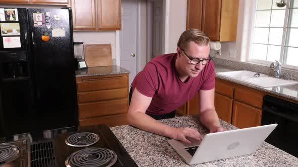 Man working on laptop computer in kitchen at home