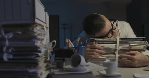 Exhausted businessman working overtime at night, he is sleeping at his desk