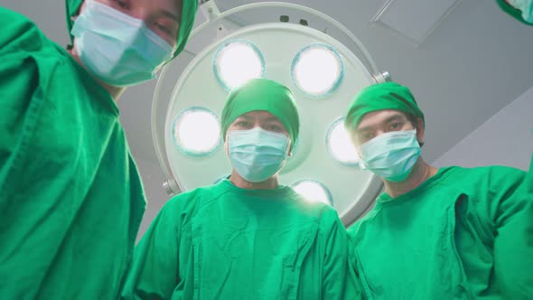 Asian professional medical team performing surgical operation in modern operating room in hospital. alt